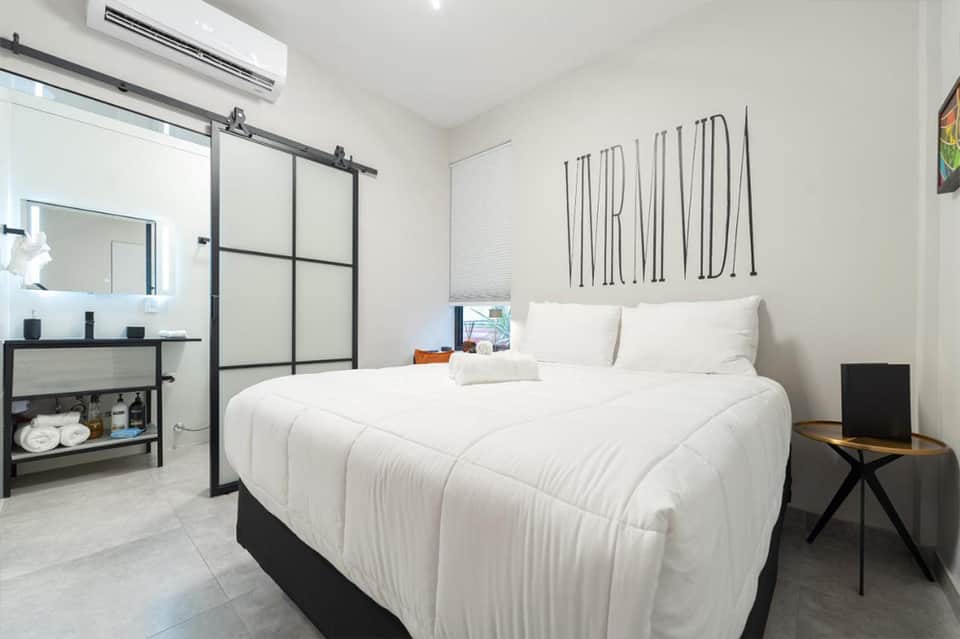 Contemporary hotel bedroom with white bedding, ensuite bathroom, and minimalist decor