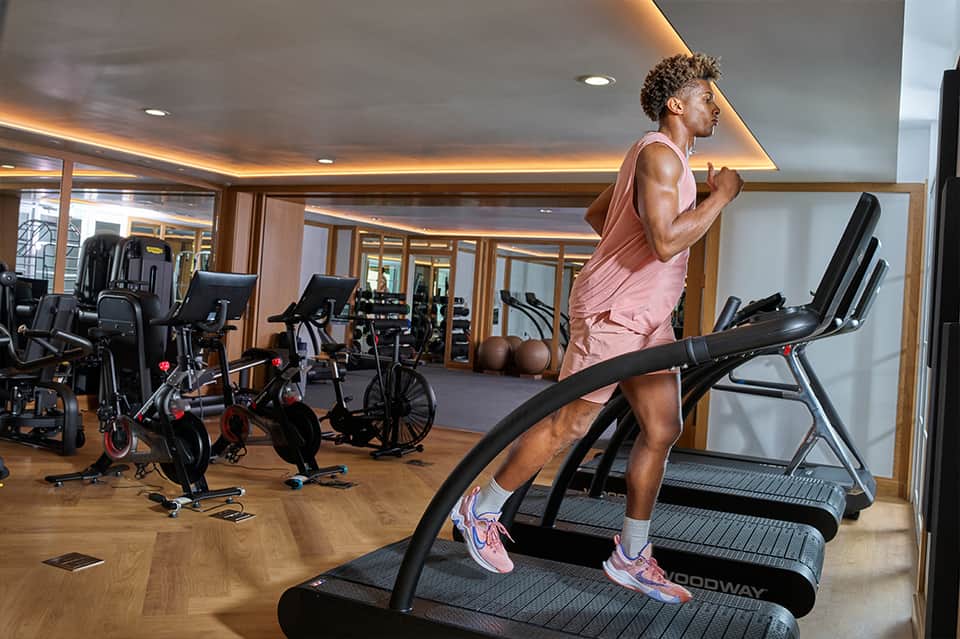 Modern fitness center with treadmill user, stationary bikes, and ambient ceiling lighting