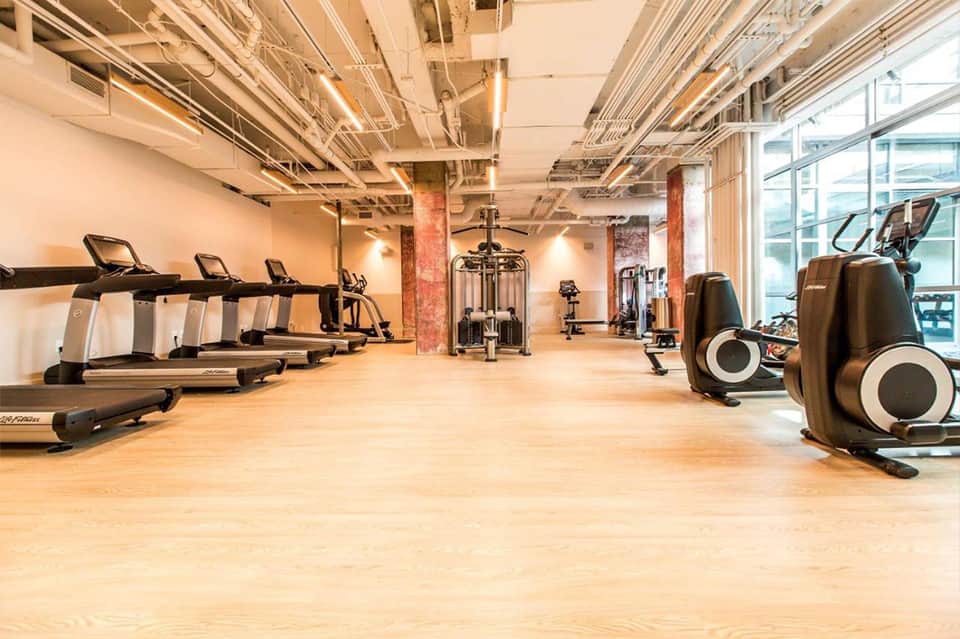 Contemporary fitness center with cardio equipment, dumbbells, and large windows