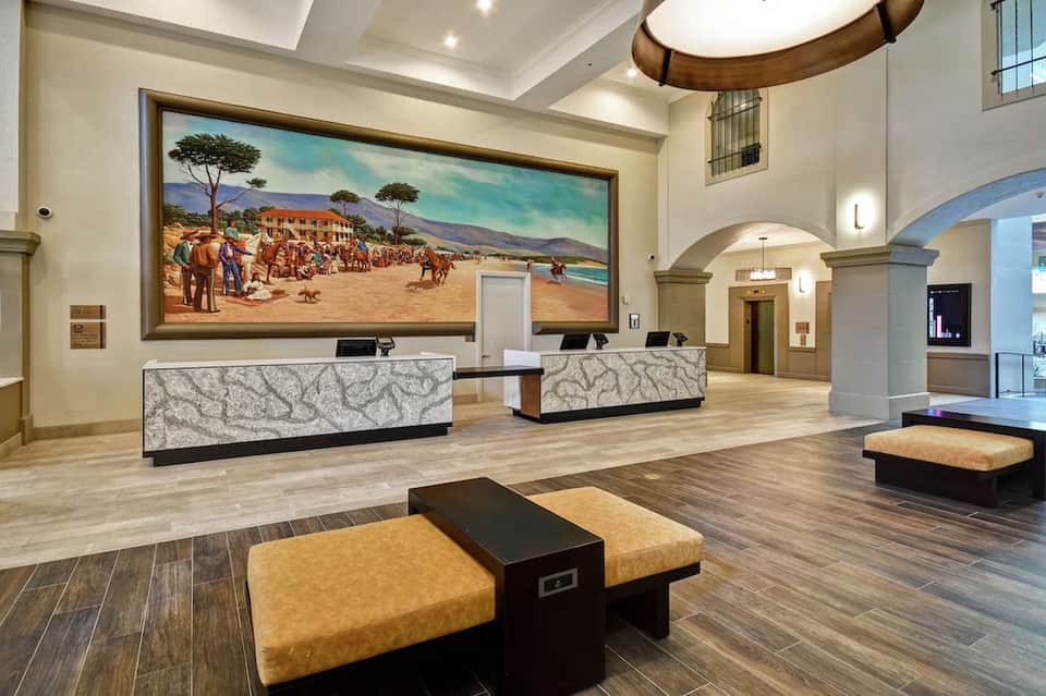 Spacious hotel lobby with dual reception desks, high ceilings, and large landscape artwork