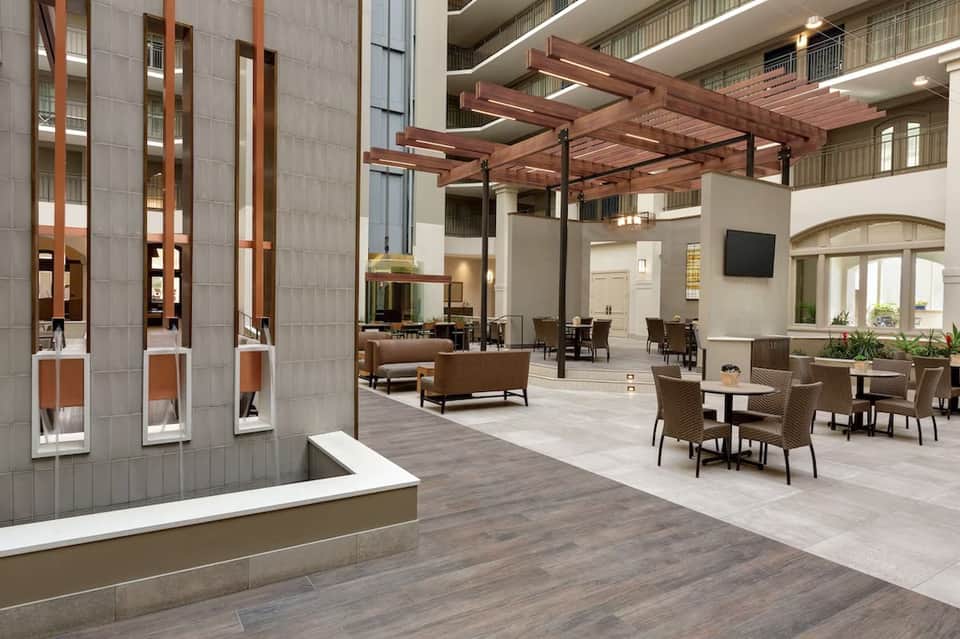 Modern hotel lobby with wooden pergola, neutral furniture, and stone accent walls