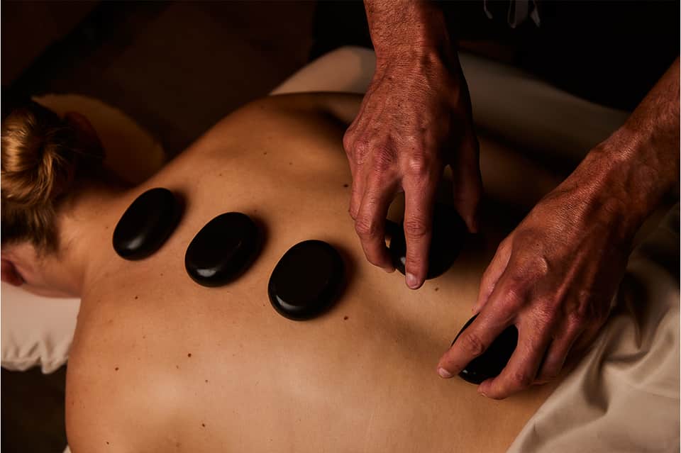 Hot stone massage therapy treatment being performed on client's back