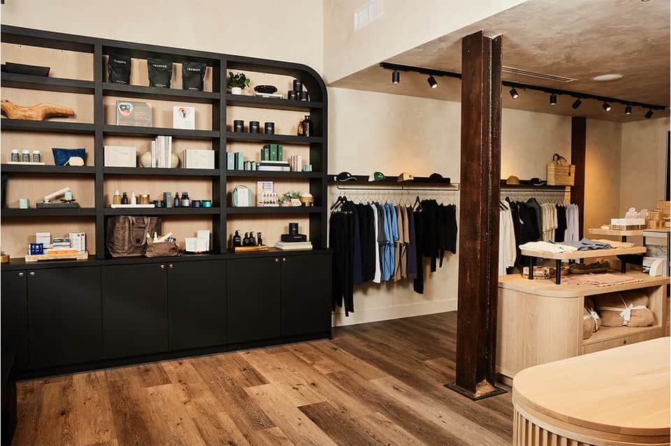 Upscale retail boutique interior with black shelving, clothing racks, and wooden display tables