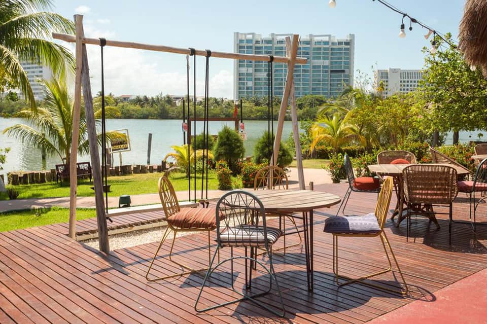 Waterfront patio with swings, dining table, and view of high-rise buildings across lake