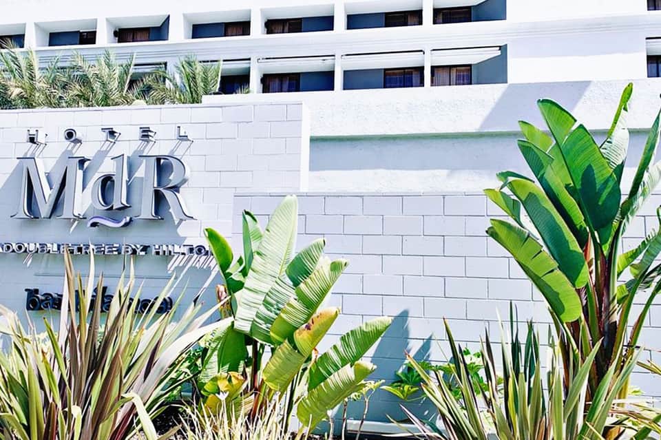 Modern white hotel building facade with MidR signage and tropical plants