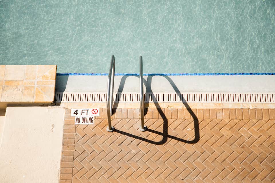 Pool edge with ladder and no diving sign at shallow end