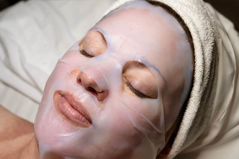 Woman wearing a pink facial mask treatment with eyes closed, spa relaxation
