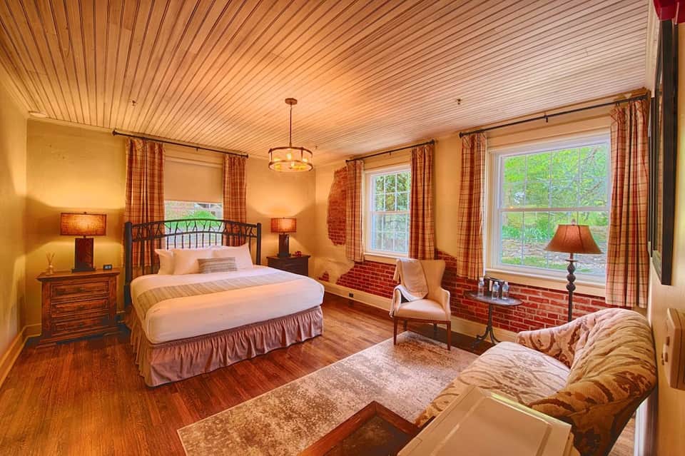 Luxurious hotel bedroom with queen bed, wood ceiling, fireplace, and plaid curtains