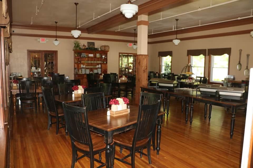 Elegant dining room with wooden beams, dark furniture, and large windows with flower centerpieces