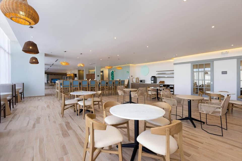 Contemporary dining area with wooden chairs, round white tables, and woven pendant lights