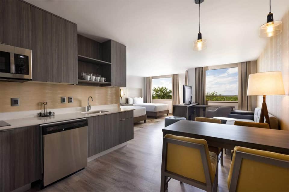 Upscale hotel suite with kitchenette, dining area, bedroom, and panoramic windows