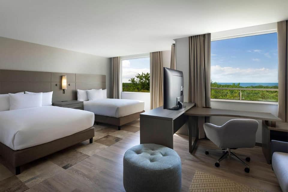 Modern hotel room with twin beds, ocean view, and contemporary furnishings