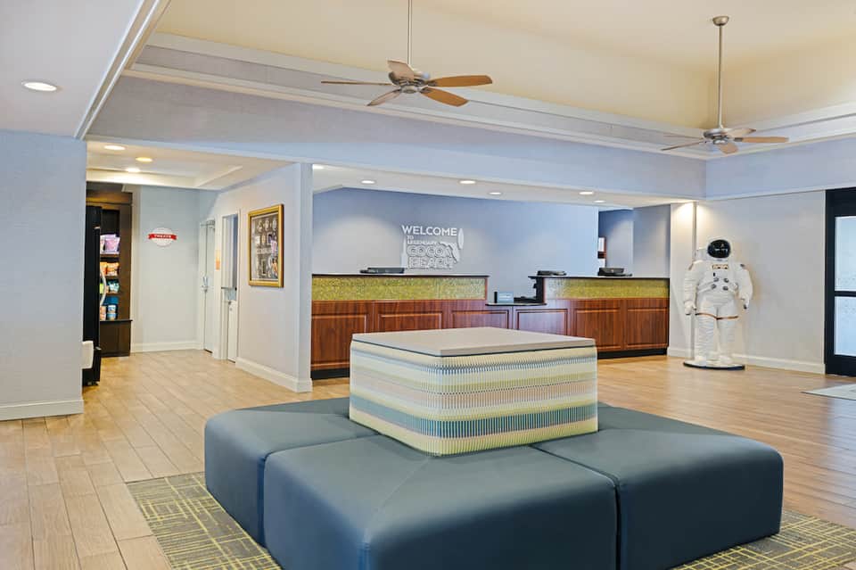 Hotel lobby interior with welcome desk, blue seating, and decorative astronaut figure