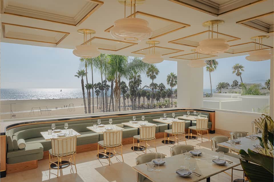 Upscale beachfront restaurant with green banquette seating, pendant lights, ocean view, palm trees