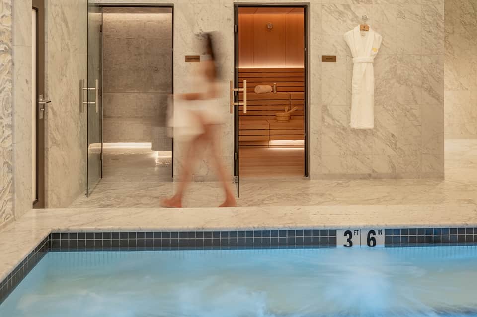 Spa area with steam sauna, shower stall, and swimming pool at hotel wellness center