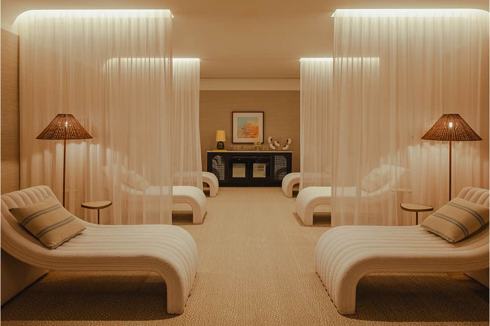 Spa relaxation room with curved cream lounges, sheer curtains, and ambient lighting