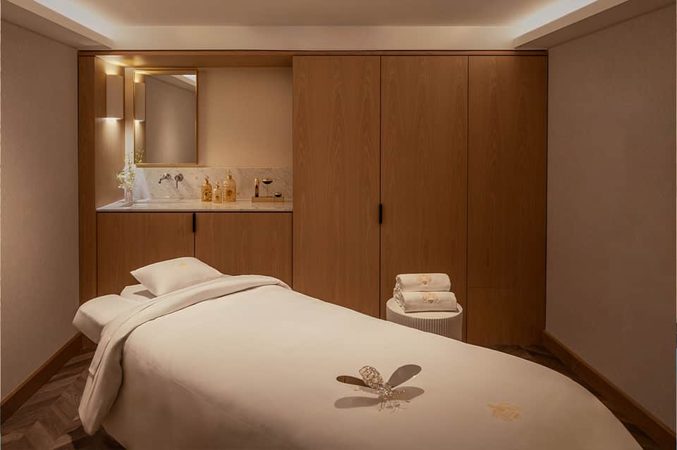 Modern spa treatment room with wooden cabinetry, massage bed, and sink area