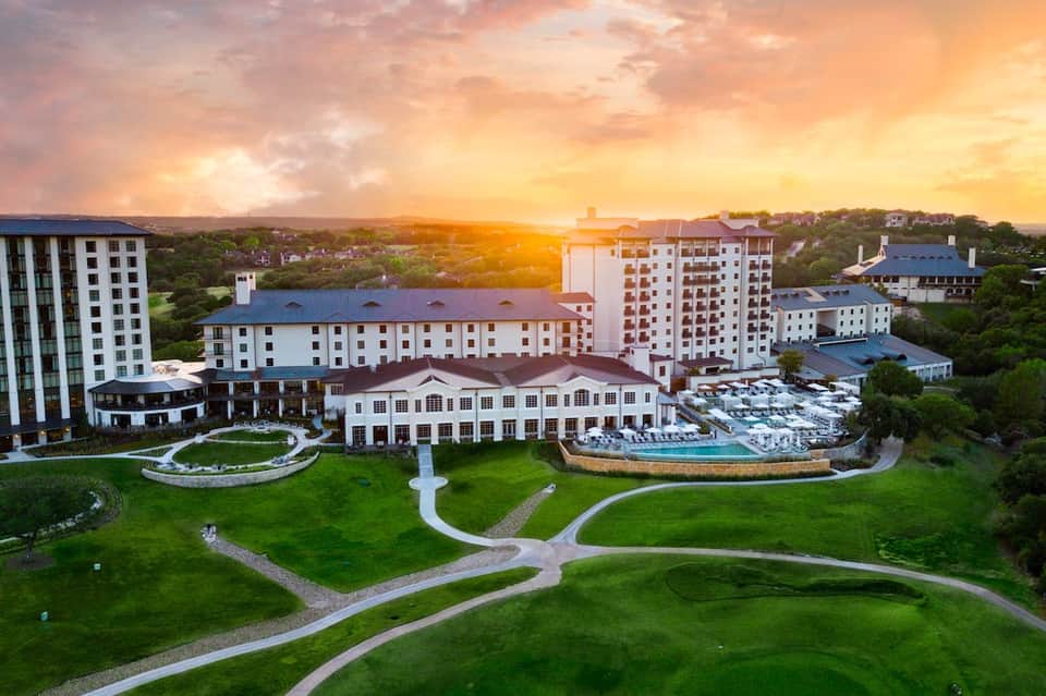 Aerial view of sprawling resort complex with multiple buildings and pools at golden hour