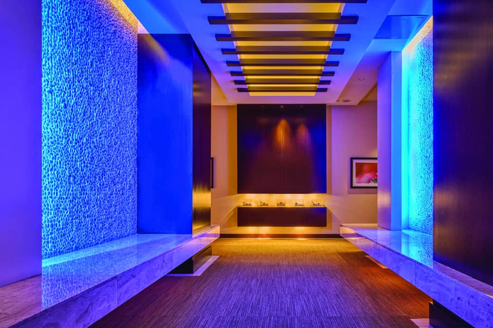 Modern spa corridor with blue and purple ambient lighting and water wall features