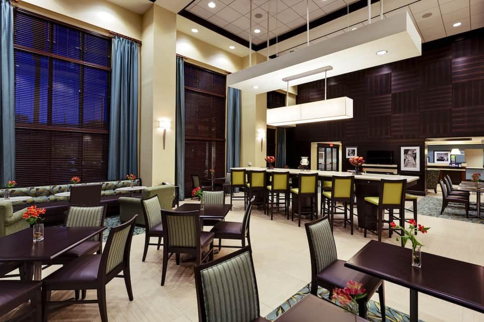 Modern hotel lounge with dark wood accents, striped chairs, high ceilings, and large windows