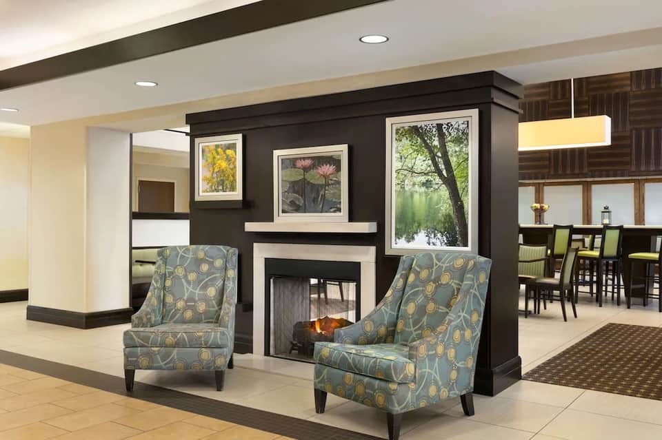 Fireplace lounge with dark accent wall, framed botanical artwork, and patterned accent chairs