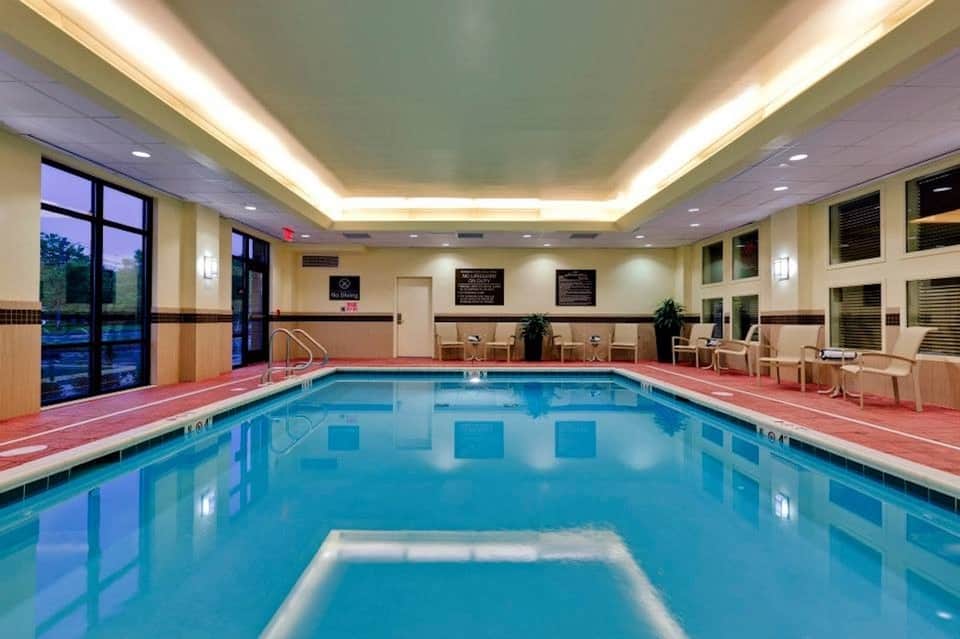 Indoor swimming pool with lane markings, lounge chairs, and large windows in modern facility