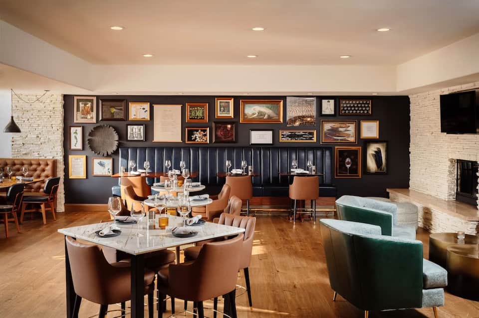 Elegant dining room with dark feature wall, gallery art, banquette seating, and fireplace