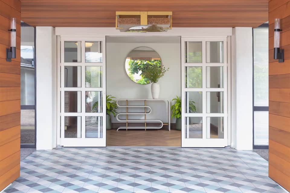 Elegant glass doors opening to a minimalist lounge with round mirror and potted plants