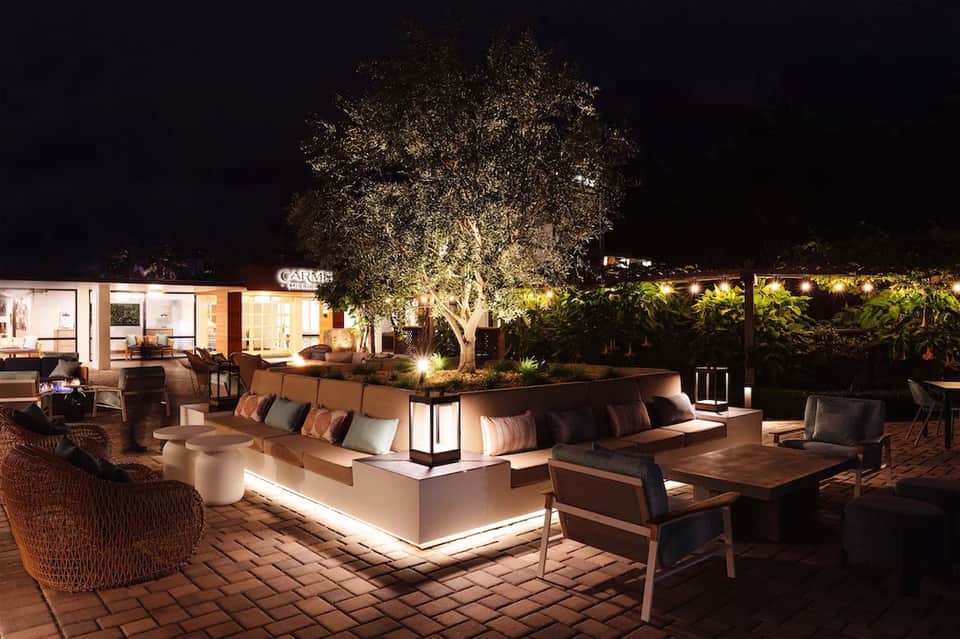 Nighttime outdoor lounge area with illuminated seating, trees, and ambient lighting