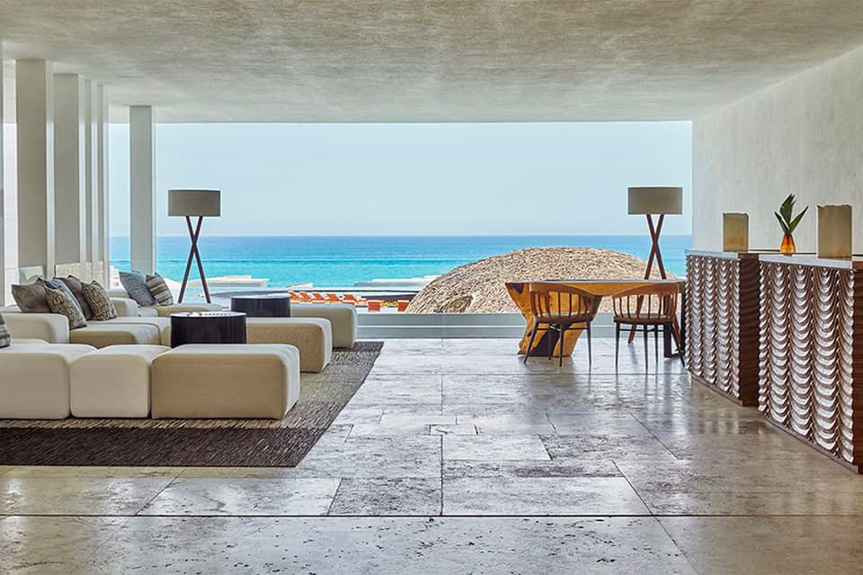 Modern beach house living area with curved sofa, ocean view, and dining space with natural light