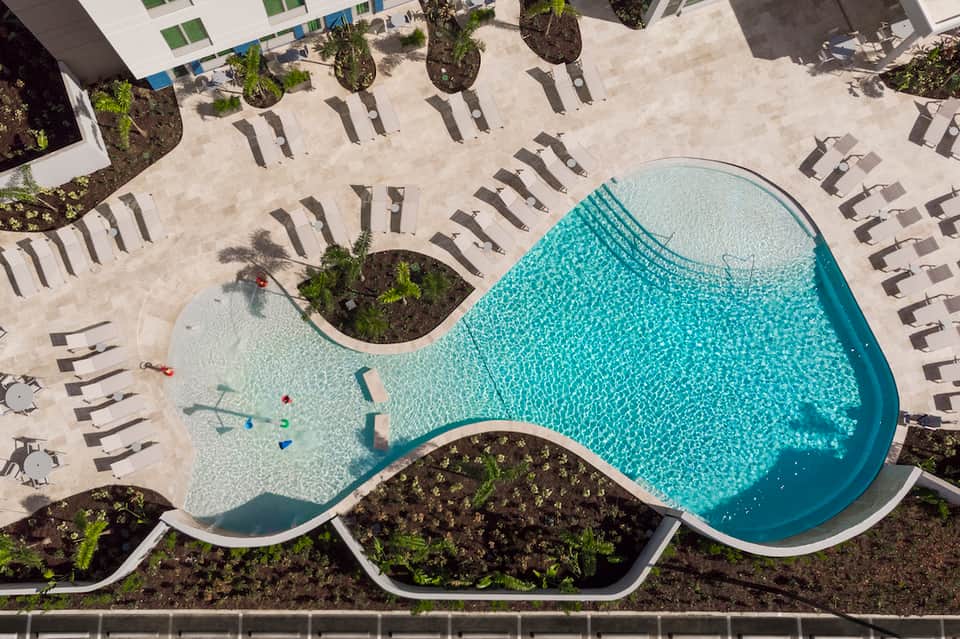 Resort pool deck with turquoise water, lounge chairs, and high-rise buildings