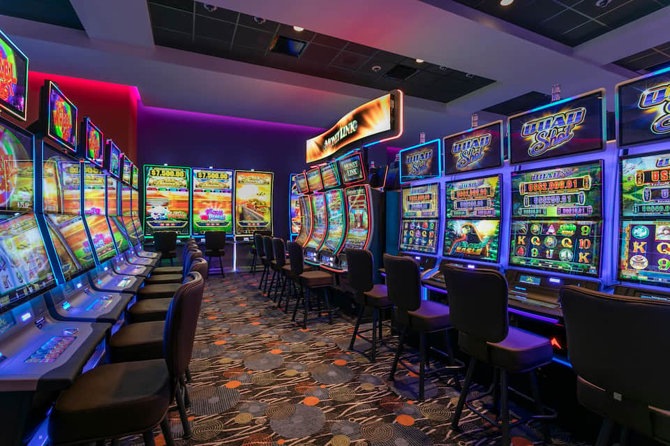 Brightly lit slot machine arcade with neon signage and colorful gaming machines