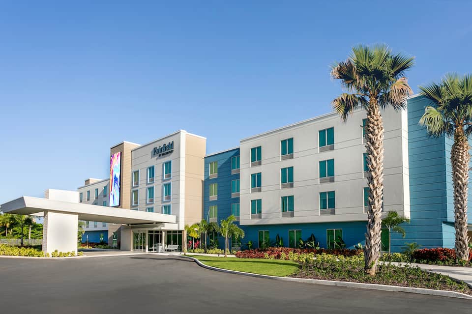 Modern Fairfield hotel exterior with blue and beige facade, palm trees, and curved driveway entrance