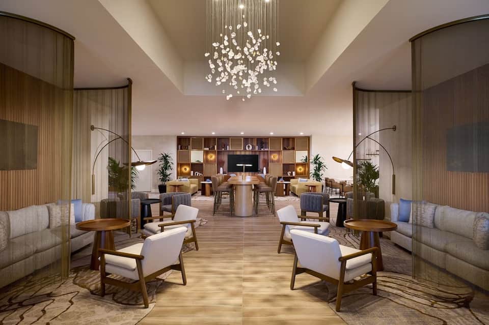 Modern hotel lobby with elegant curved furniture, crystal chandelier, and symmetrical design in warm tones