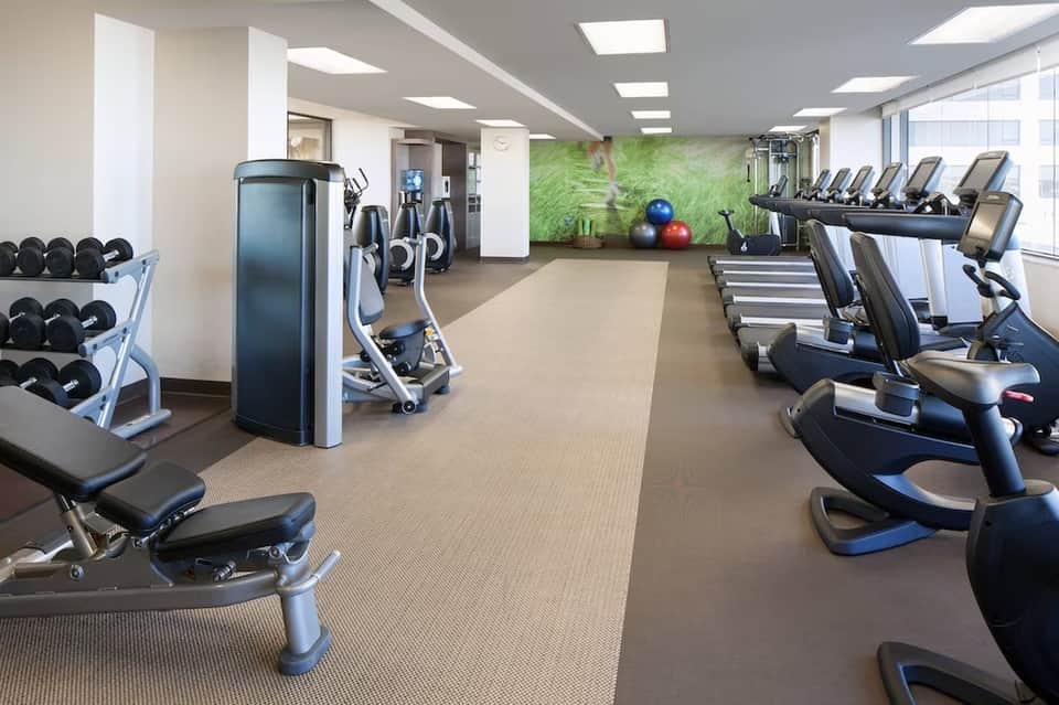 Fitness center with cardio equipment, dumbbells, and green accent wall
