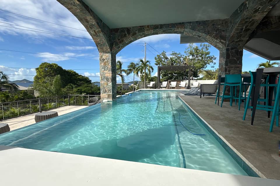 Lap pool under covered structure with mountain and tropical landscape views