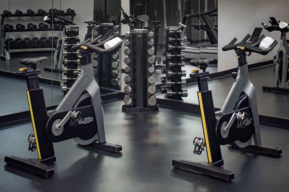 Fitness center with stationary bikes, dumbbells on racks, and exercise equipment
