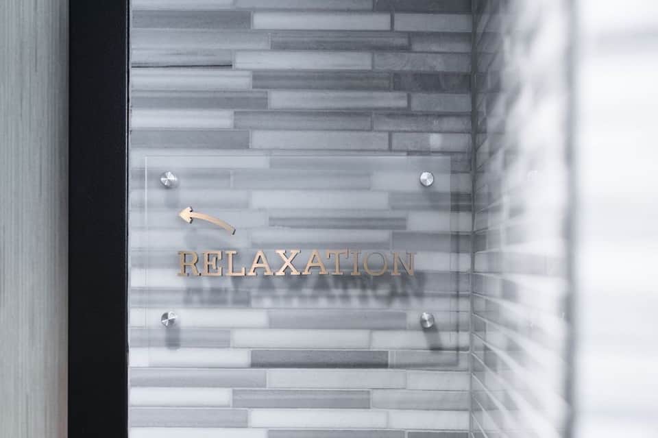 Glass door entrance to relaxation spa area with tile flooring and bronze lettering