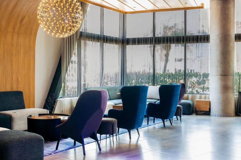 Modern hotel lobby lounge with blue velvet chairs and floor-to-ceiling windows