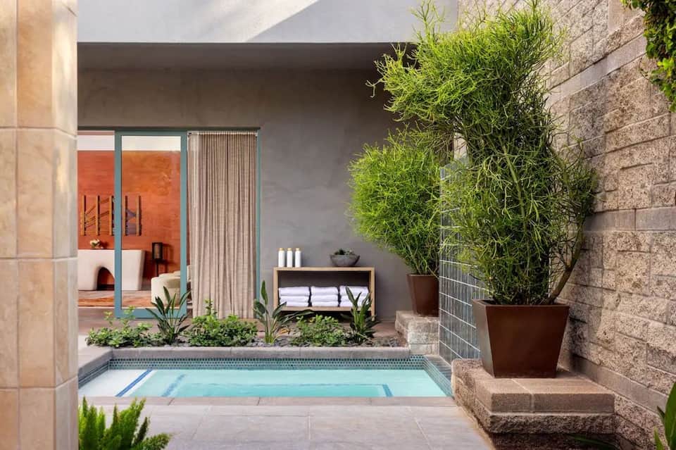 Modern courtyard with small pool, stone walls, potted plants, and spa entrance