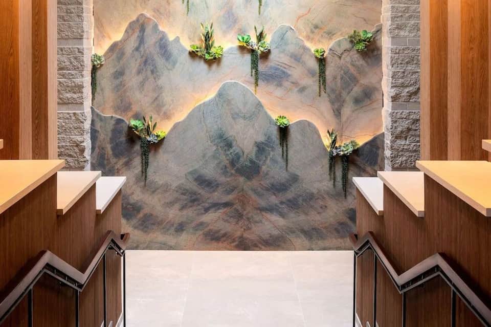 Modern spa stairwell with mountain landscape mural, illuminated backdrop, succulent planters, and warm wood paneling