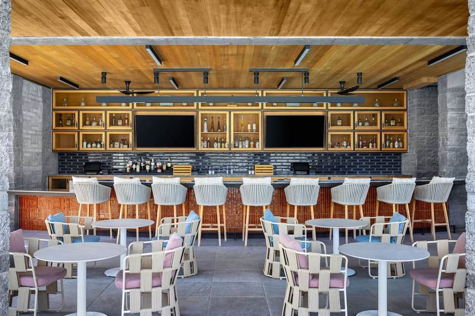 Contemporary bar and lounge area with wooden ceiling, bar seating, and dining tables