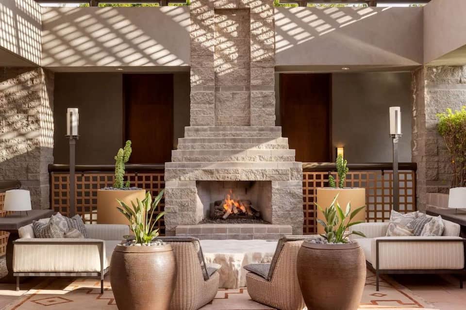 Outdoor courtyard with central fireplace, lounge seating, and pergola shade structure