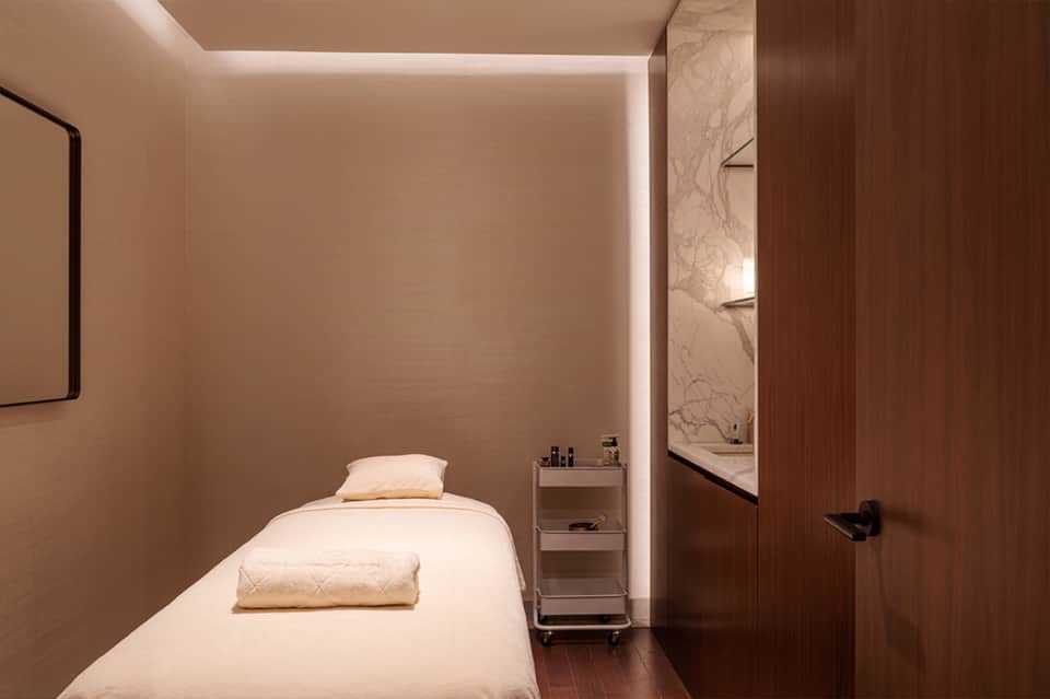 Minimalist spa treatment room with massage bed, ambient lighting, and marble accents
