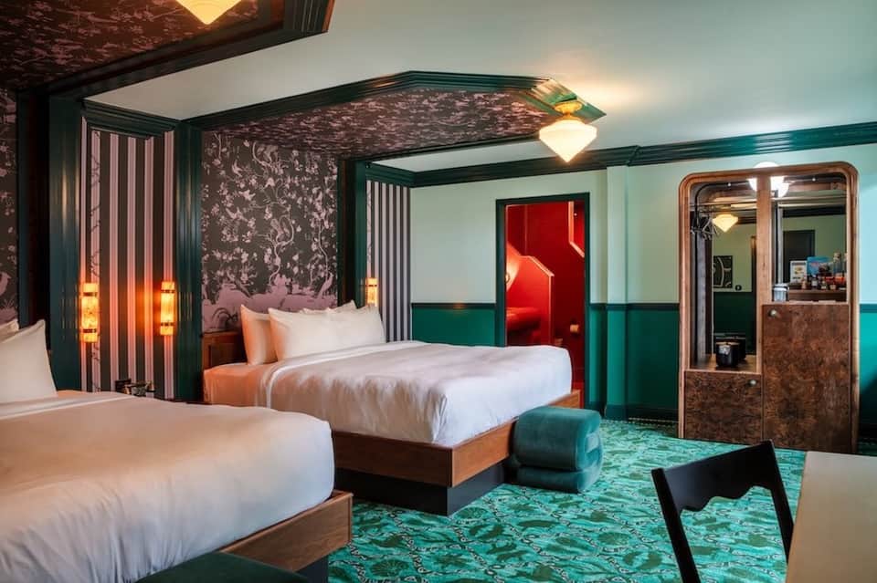 Luxury hotel bedroom with canopy bed, teal accents, and ornate patterned headboard