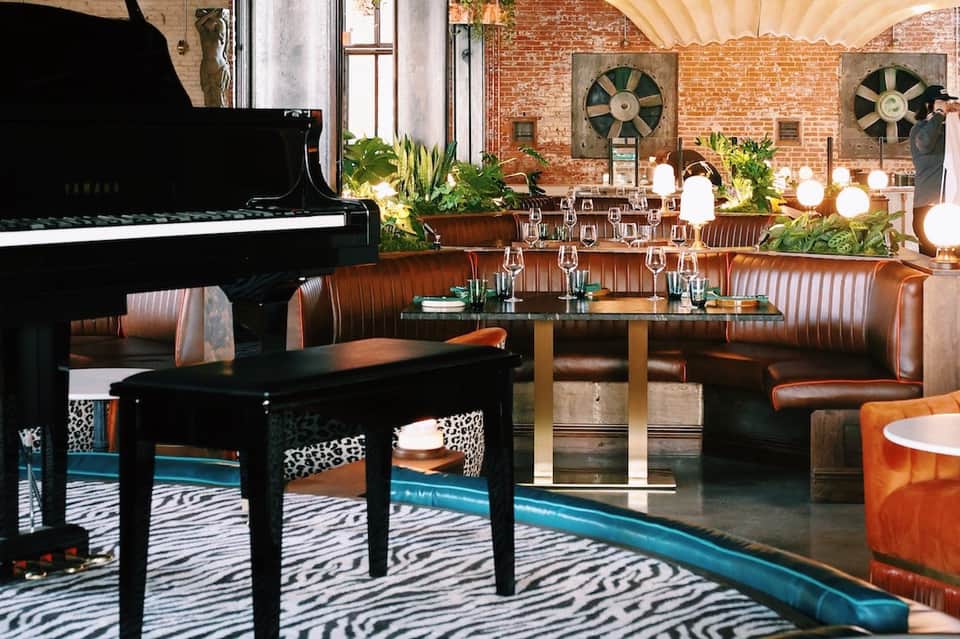 Modern event space with grand piano, exposed brick walls, leather seating, and industrial design elements