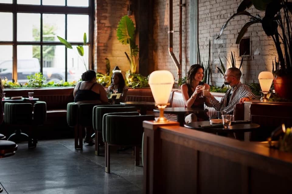 Upscale hotel lounge bar with ambient lighting, plants, comfortable seating, and large windows