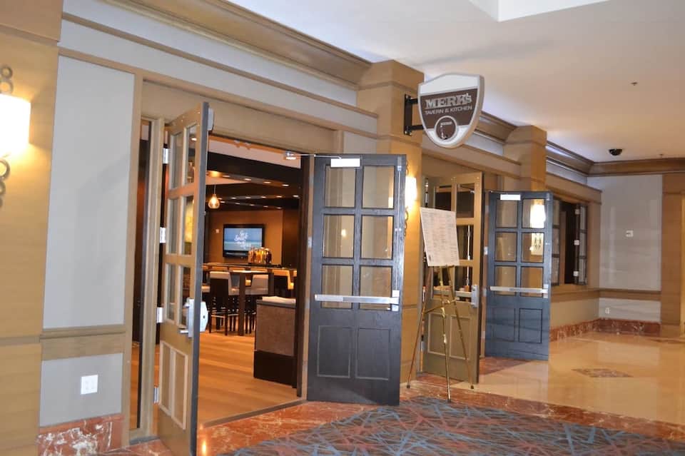 Hotel corridor with wooden beams, glass doors, and restaurant entrance signage