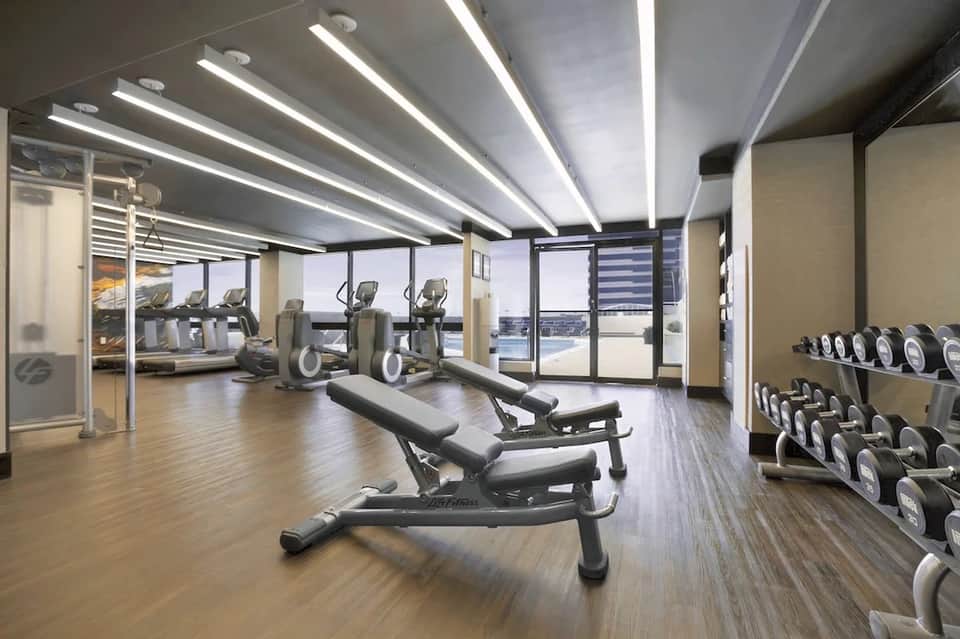 Modern hotel fitness center with cardio equipment, free weights, and floor-to-ceiling windows