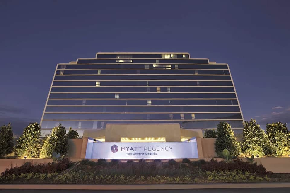 Modern hotel exterior at dusk showing illuminated geometric glass facade with Hyatt Regency signage